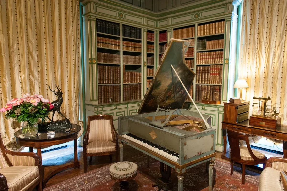 Library with grand piano inside Château de Cheverny on a Loire Valley castle tour
